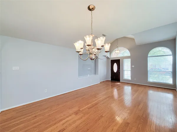 a view of a room with a chandelier and wooden floors