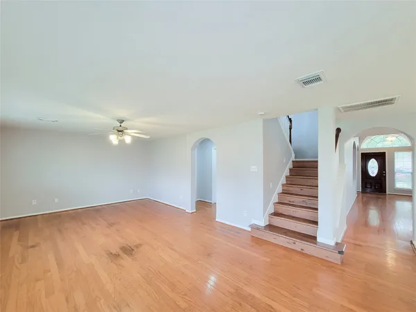 a view of an empty room with stairs and a chandelier fan