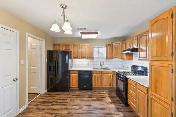 a large kitchen with stainless steel appliances granite countertop a refrigerator a sink dishwasher a dining table and chairs with wooden floor