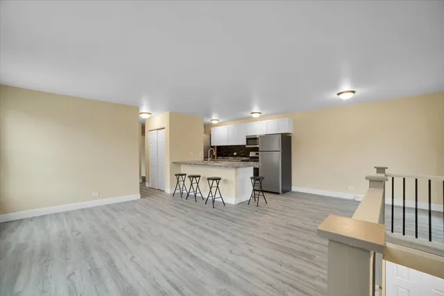 a kitchen with stainless steel appliances granite countertop a stove a sink a refrigerator white cabinets and wooden floor