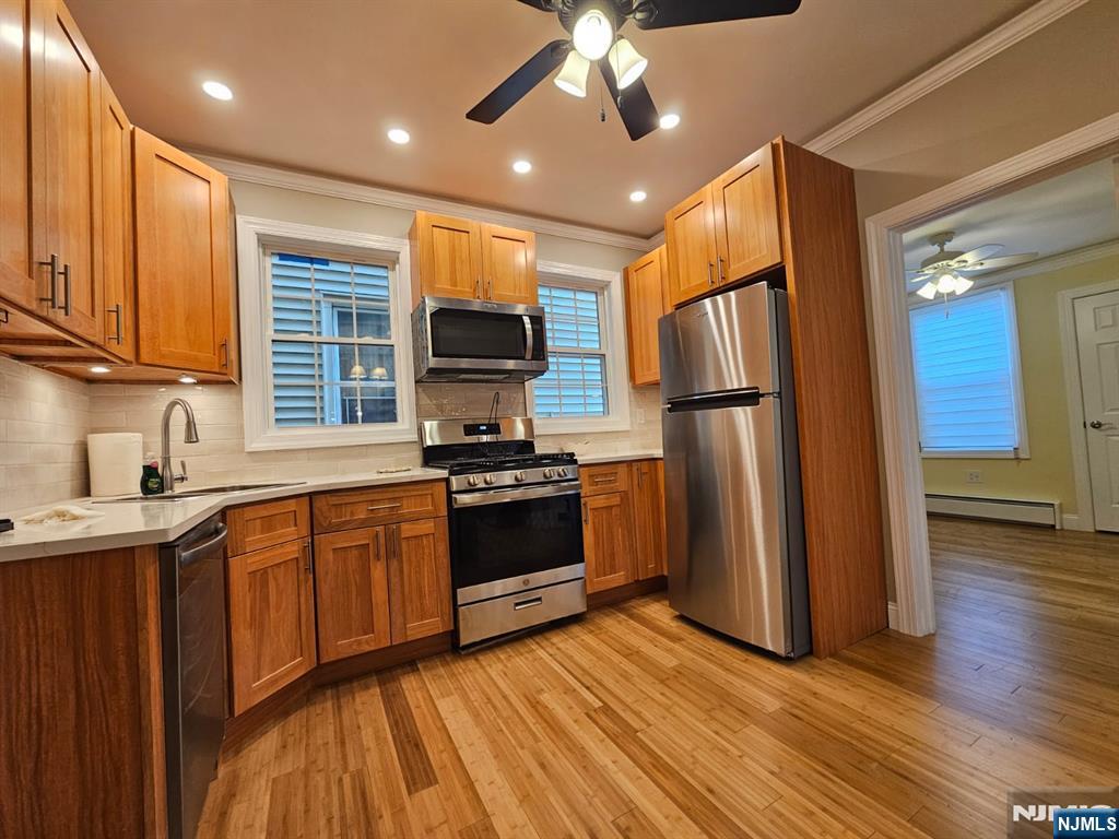 a kitchen with stainless steel appliances granite countertop a refrigerator a sink dishwasher a stove and white countertops with wooden floor