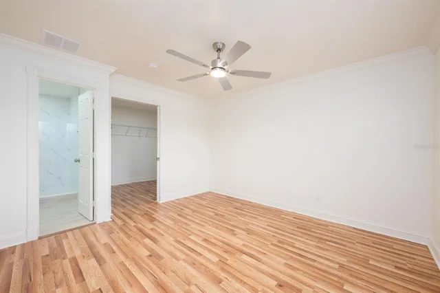 an empty room with wooden floor fan and windows