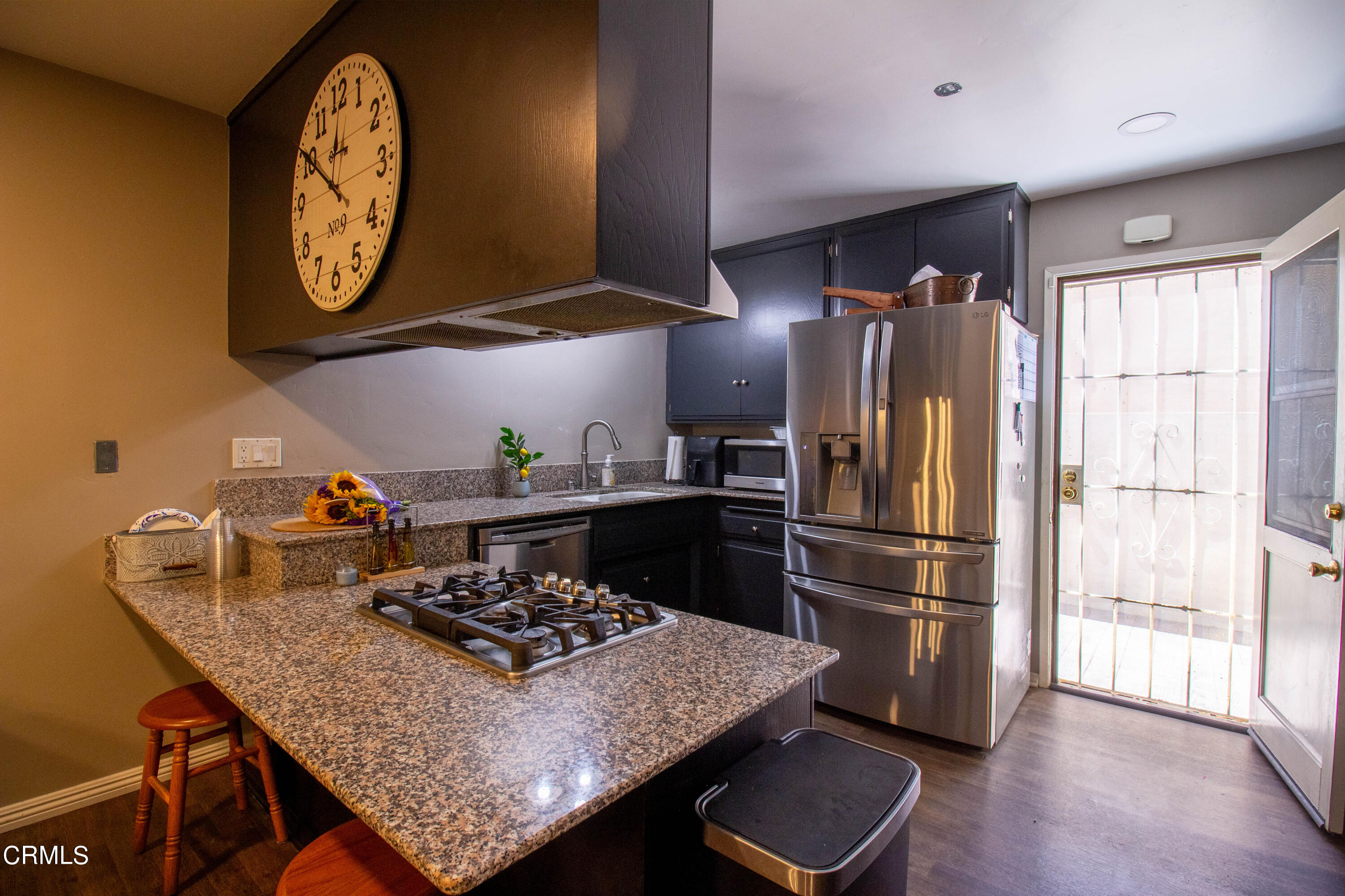 1300 Bluebell Street Oxnard, CA 93036 - Photo 6 of 24 a kitchen with stainless steel appliances granite countertop a stove a refrigerator a dining table and chairs with wooden floor
