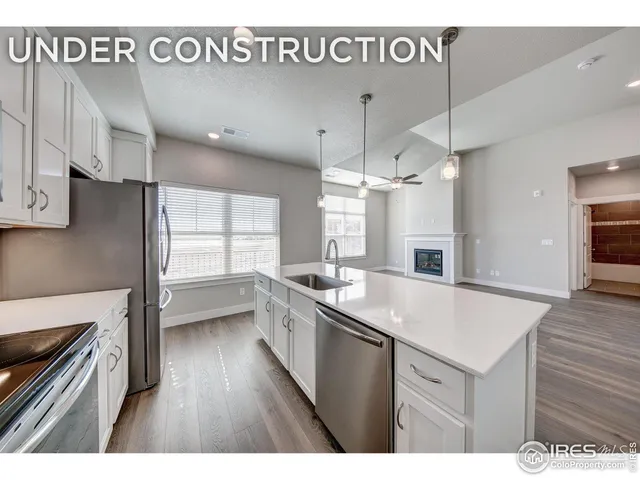 a kitchen with a sink appliances wooden floor and a window
