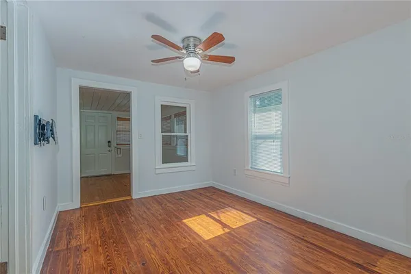 a view of empty room with wooden floor and fan
