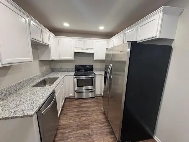 a kitchen with stainless steel appliances granite countertop a refrigerator a stove a sink and a microwave