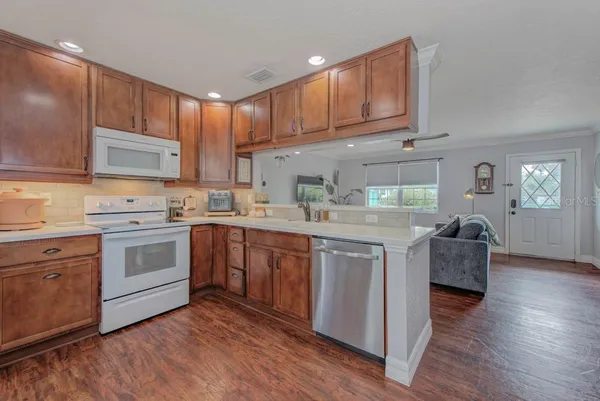 a kitchen with stainless steel appliances granite countertop a stove top oven a sink dishwasher and cabinets with wooden floor