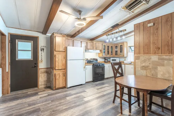 a kitchen with stainless steel appliances granite countertop a dining table chairs refrigerator and cabinets