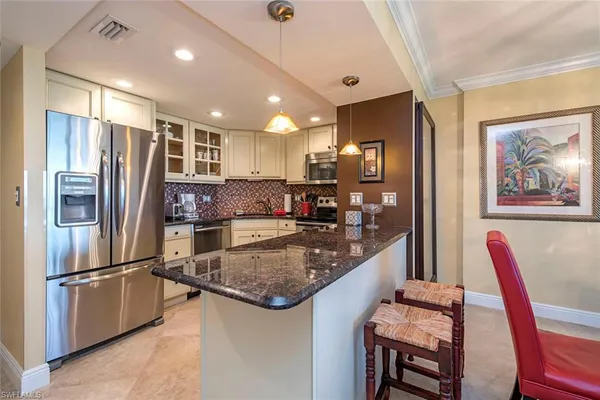 a kitchen with stainless steel appliances granite countertop a refrigerator a stove a sink a dining table and chairs