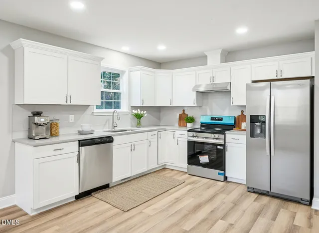 a kitchen with granite countertop a refrigerator sink and white cabinets