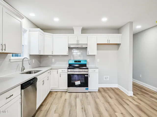 a kitchen with stainless steel appliances granite countertop a stove and white cabinets