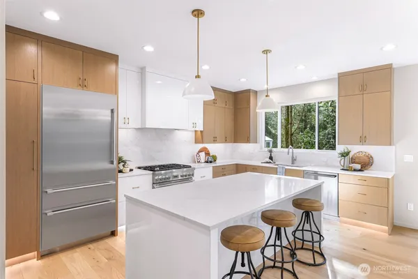 a kitchen with stainless steel appliances granite countertop a sink a stove a refrigerator and island with wooden floor