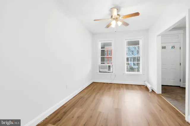 an empty room with wooden floor chandelier fan and windows