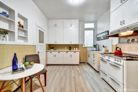 a kitchen that has a lot of white cabinets a sink and wooden floor