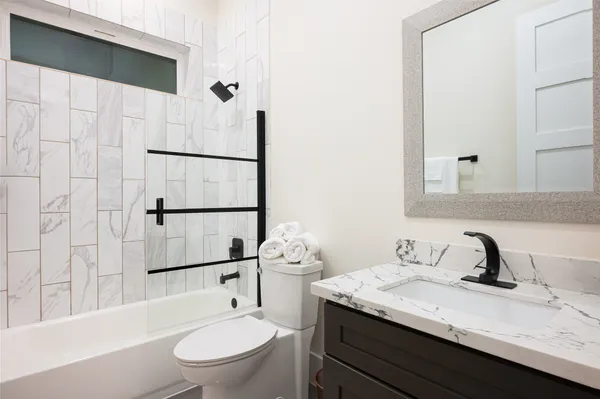 a bathroom with a granite countertop sink toilet a mirror and shower