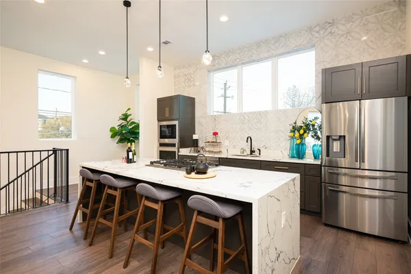 a kitchen with stainless steel appliances a dining table chairs sink refrigerator and microwave