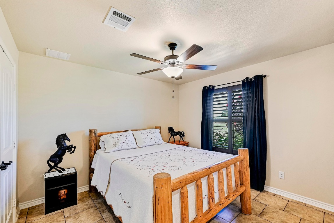 560 Saddle Ridge Drive Bertram, TX 78605 - Photo 13 of 27 a bedroom with a large bed and a chandelier