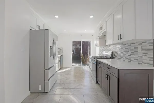 a kitchen with stainless steel appliances granite countertop a refrigerator and a stove top oven