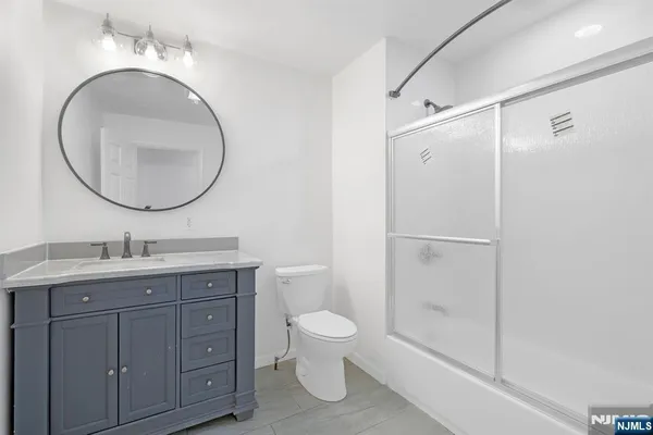 a bathroom with a granite countertop toilet a sink and a mirror