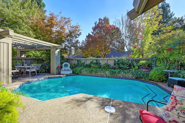 a view of a patio with table and chairs potted plants and large tree