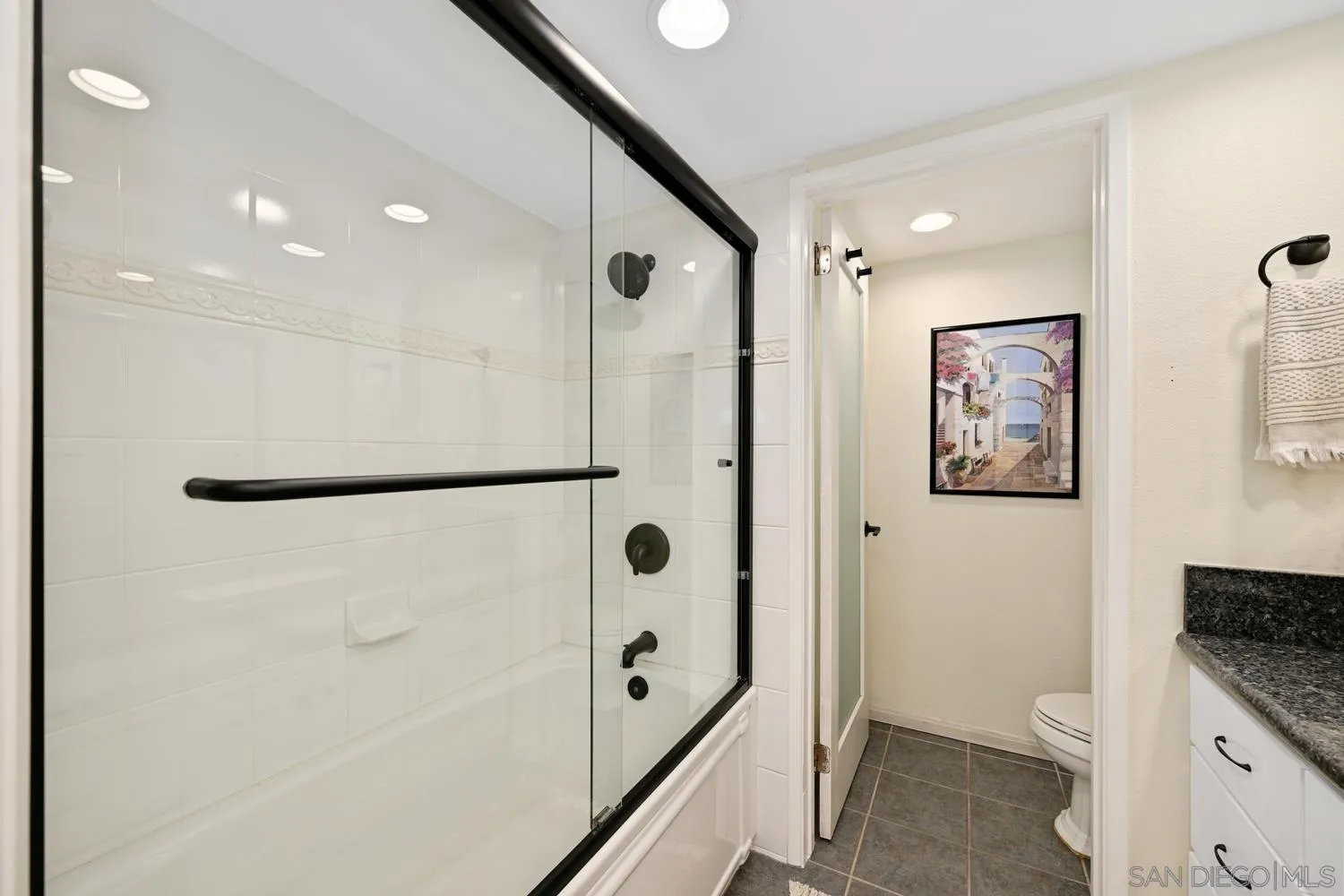 1270 Cleveland Avenue, Unit F246 San Diego, CA 92103 - Photo 16 of 23 a bathroom with a granite countertop sink a mirror a shower and a bathtub