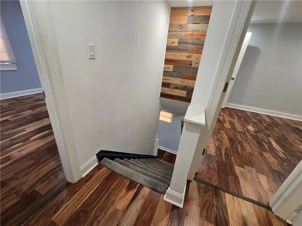 a view of an empty room with wooden floor and stairs