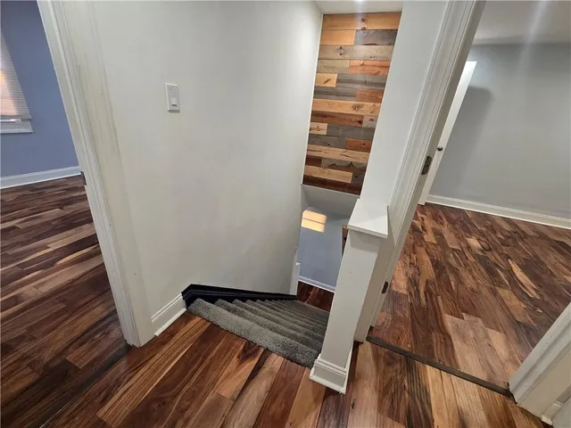 a view of an empty room with wooden floor and stairs