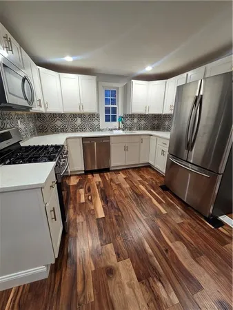 a kitchen with granite countertop a refrigerator a sink and white cabinets