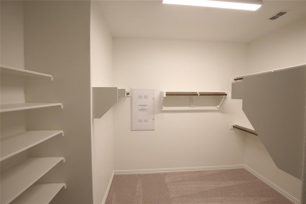 15142 Rosario Road Frisco, TX 75035 - Photo 12 of 21 Walk-in closet featuring white painted walls and trim, carpeted flooring, built-in shelving, and clothes hanging rods