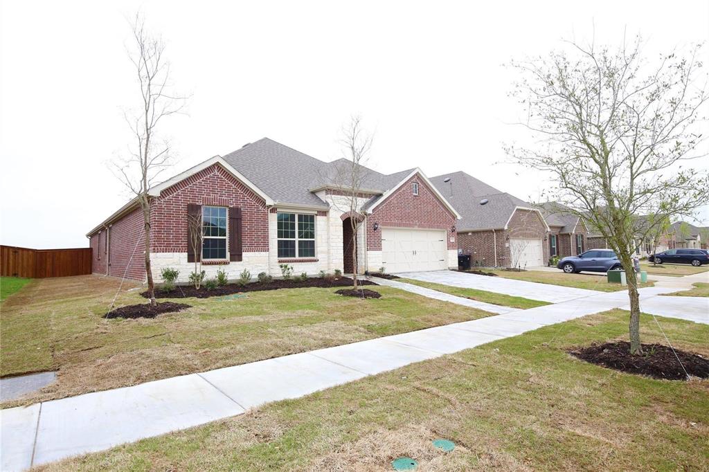 15142 Rosario Road Frisco, TX 75035 - Photo 2 of 21 Brick and stone facade residence featuring a front-facing garage, dark wood-finish shutters, and a concrete walkway