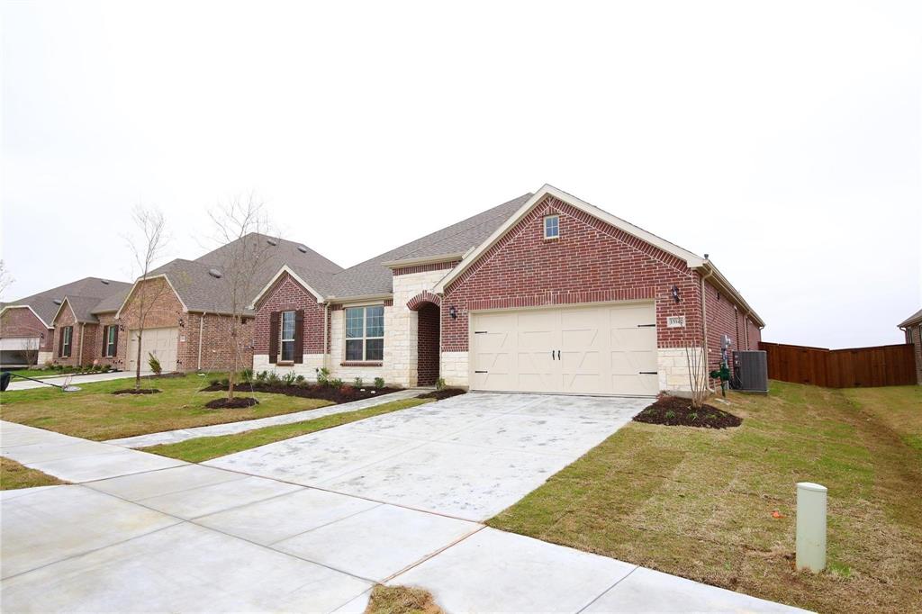 15142 Rosario Road Frisco, TX 75035 - Photo 3 of 21 Brick and stone facade residence featuring an attached garage with a light-colored door, an asphalt shingle roof, and a concrete driveway