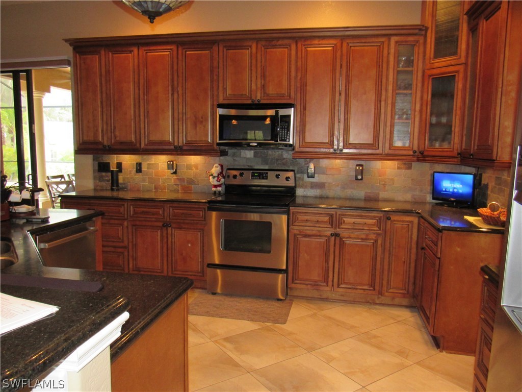 31031 Oil Well Road Punta Gorda, FL 33955 - Photo 4 of 22 a kitchen with stainless steel appliances granite countertop a stove a sink dishwasher and a microwave oven with cabinets
