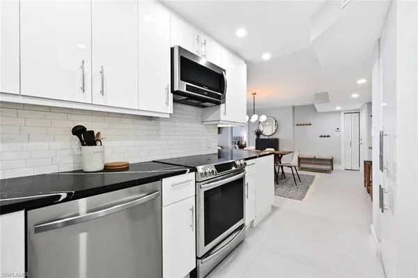 a kitchen with stainless steel appliances a sink dishwasher a stove and a microwave oven on granite countertops