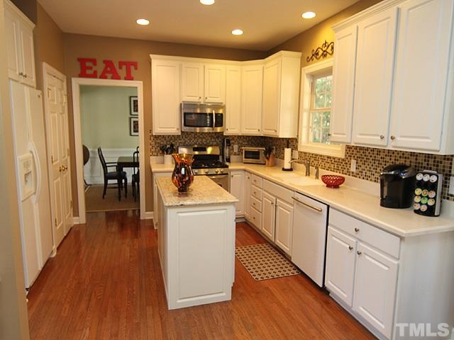 1508 Wood Spring Court Raleigh, NC 27614 - Photo 6 of 25 a kitchen with stainless steel appliances a stove top oven a sink a refrigerator white cabinets and wooden floor