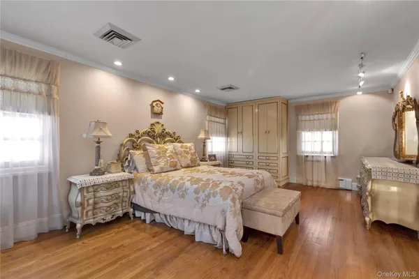 a spacious bedroom with a bed and wooden floor