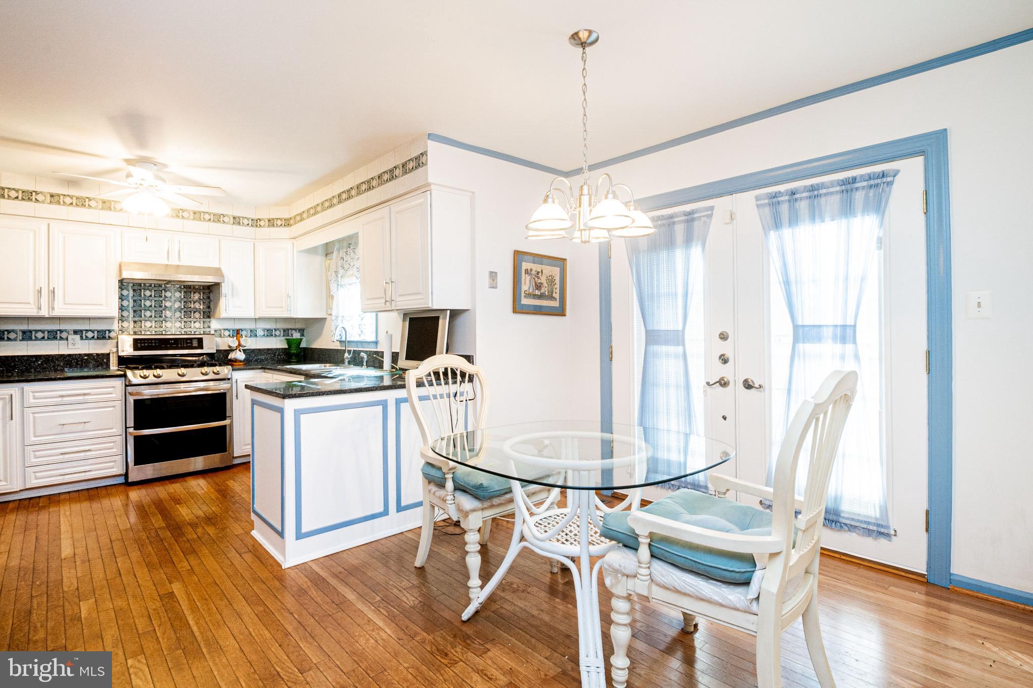 4910 Grid Street Bowie, MD 20720 - Photo 9 of 29 a kitchen with stainless steel appliances granite countertop a refrigerator a stove a sink dishwasher a dining table and chairs with wooden floor