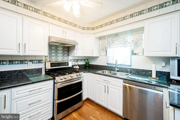 a kitchen with granite countertop a stove sink and cabinets