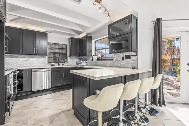 a kitchen with stainless steel appliances granite countertop wooden cabinets a sink and dishwasher next to a window