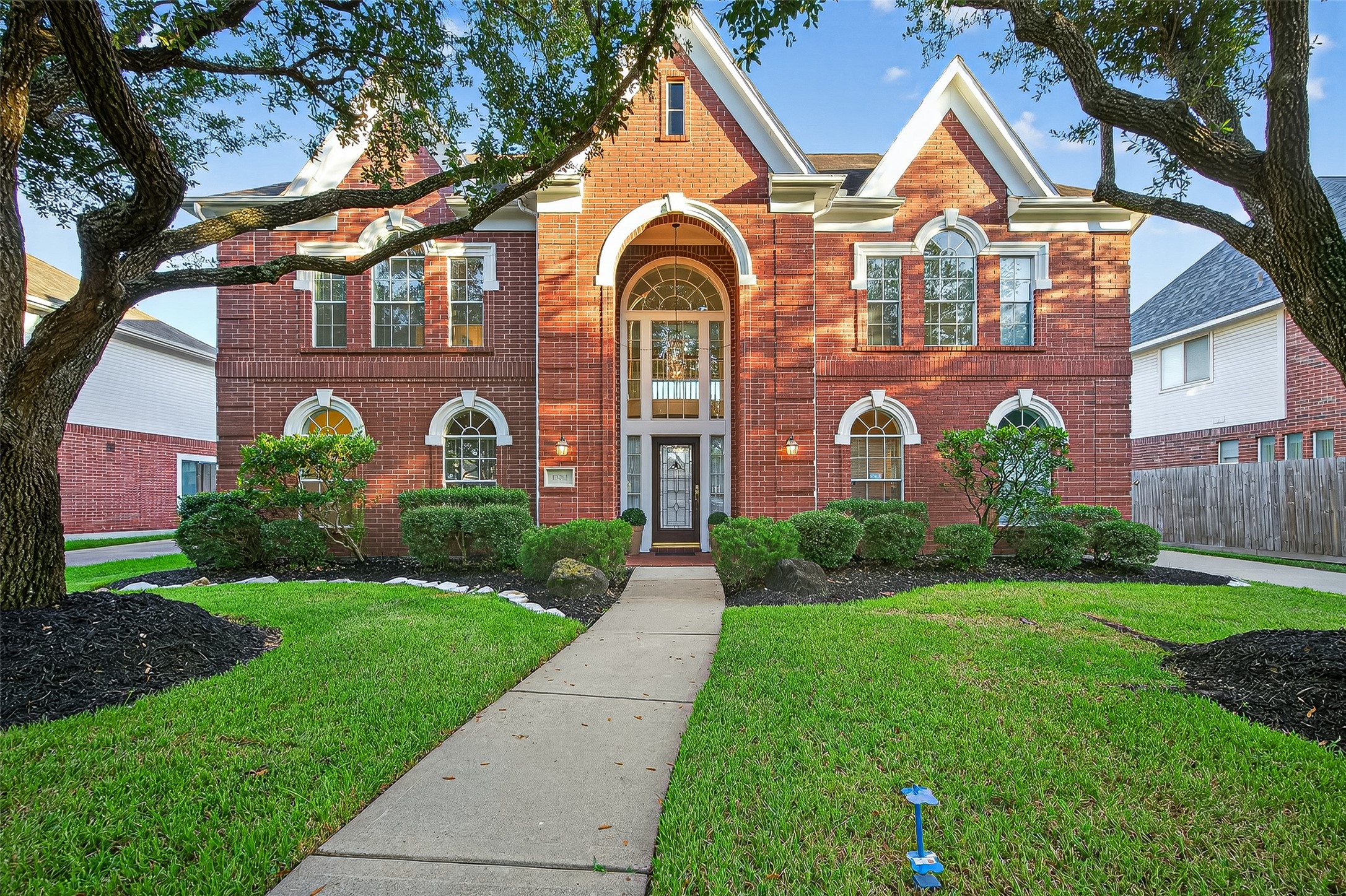 13011 Mossy Ridge Cove Houston, TX 77041 - Photo 45 of 50 This is a stunning two-story red brick home with elegant arched windows and a grand entrance. It features a well-maintained lawn and tasteful landscaping, creating an inviting curb appeal.