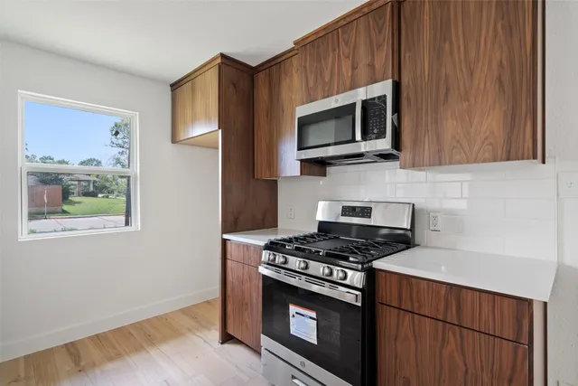 a kitchen with stainless steel appliances a stove a microwave a sink and cabinets