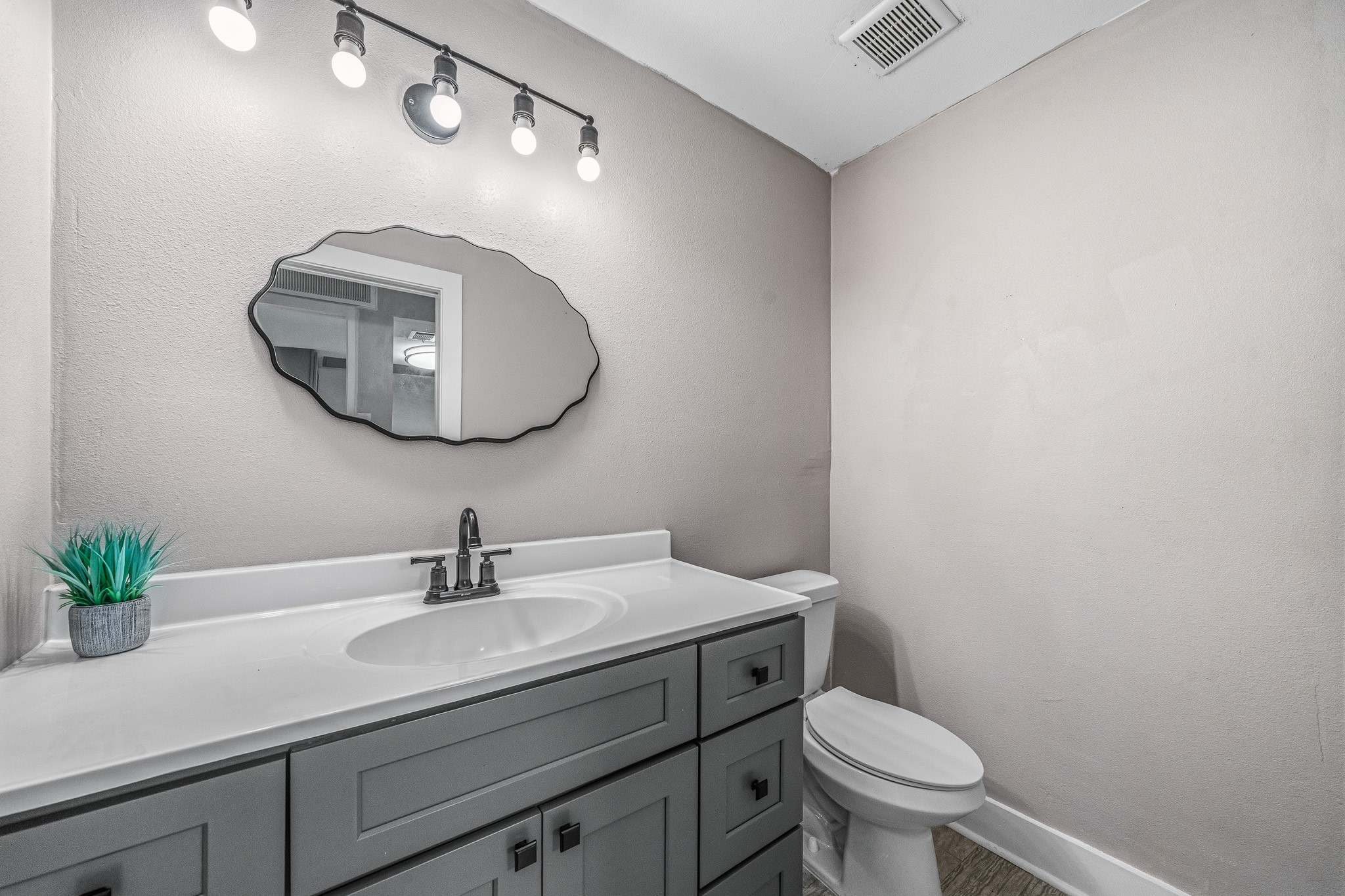 830 Threadneedle Street, Unit 240 Houston, TX 77079 - Photo 12 of 33 This photo shows a modern bathroom with a sleek gray vanity, stylish mirror, and bright lighting. The space is complemented by a decorative plant and neutral wall colors, creating a clean and inviting atmosphere.