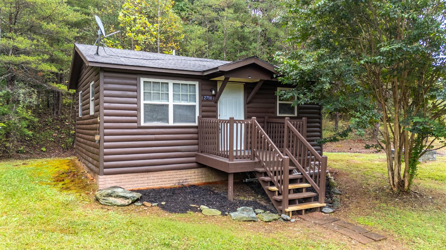a view of a small house with a small deck and a large tree
