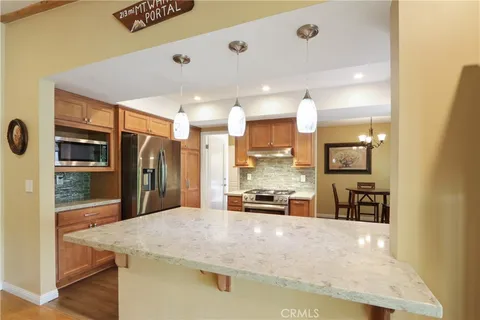 a kitchen with stainless steel appliances kitchen island granite countertop a refrigerator a stove and a sink with wooden floor