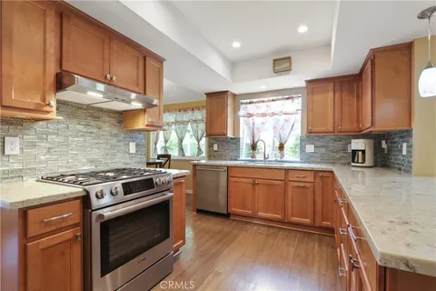 a kitchen with stainless steel appliances wooden floor sink stove and cabinets