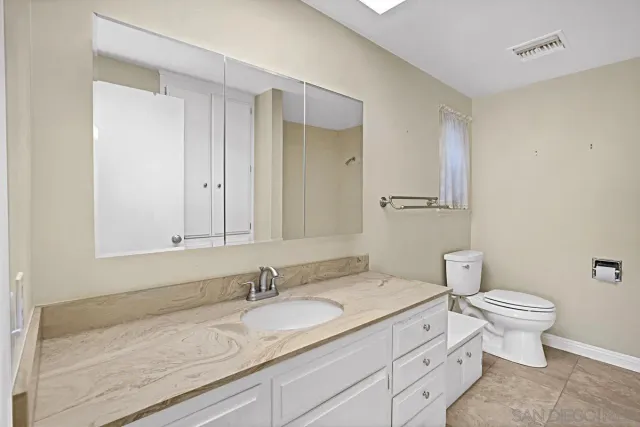 a bathroom with a granite countertop sink and a toilet