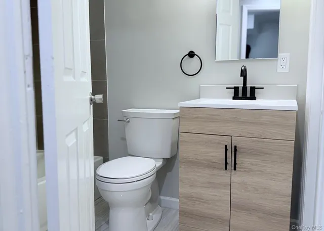 a bathroom with a toilet sink vanity and mirror