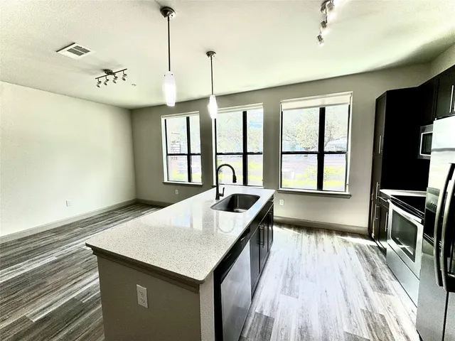 a view of a kitchen with a sink a window and wooden floor