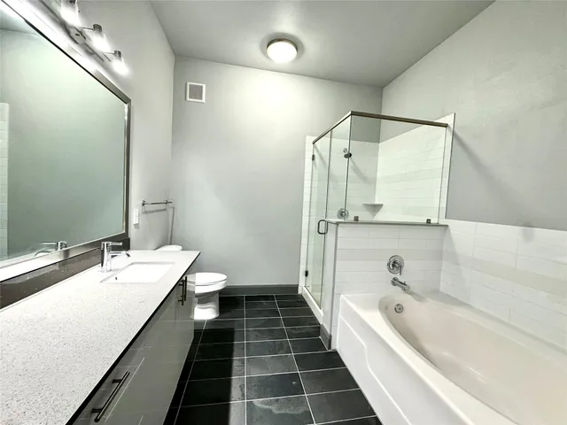a bathroom with a double vanity sink and mirror with bathtub