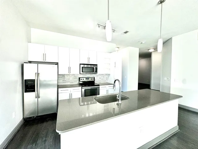 a kitchen with stainless steel appliances granite countertop a refrigerator a sink and a stove