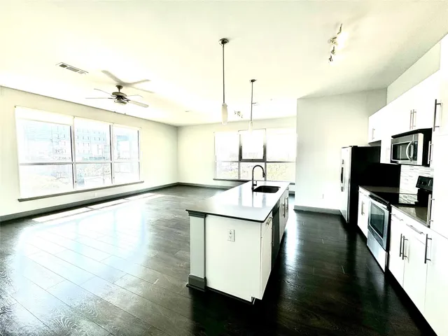 a kitchen with stainless steel appliances granite countertop a sink a stove and a wooden floors